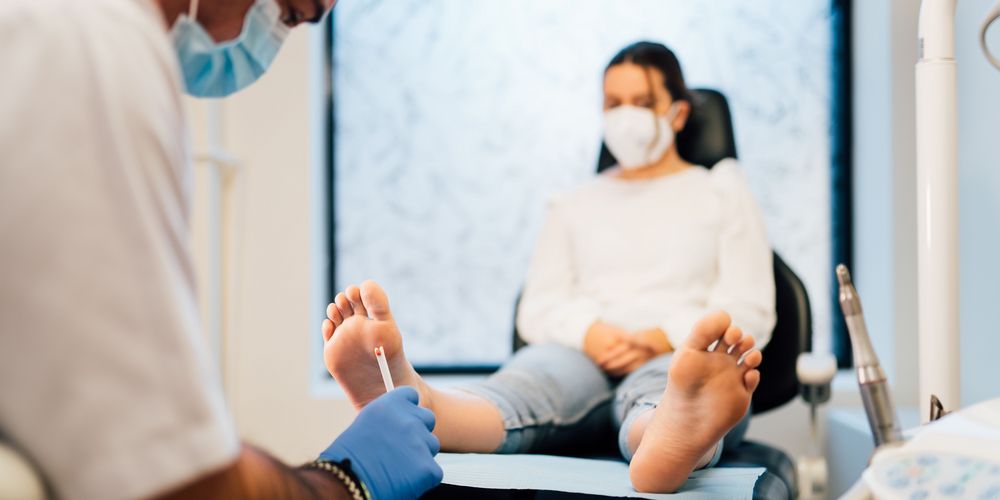 Ein Arzt untersucht den Fuß einer Patientin auf chronische Wunden.