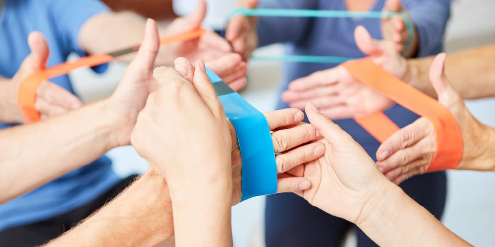 Mehrere Patientinnen und Patienten führen gemeinsam Übungen in einer Gruppensitzung zur Ergotherapie durch.