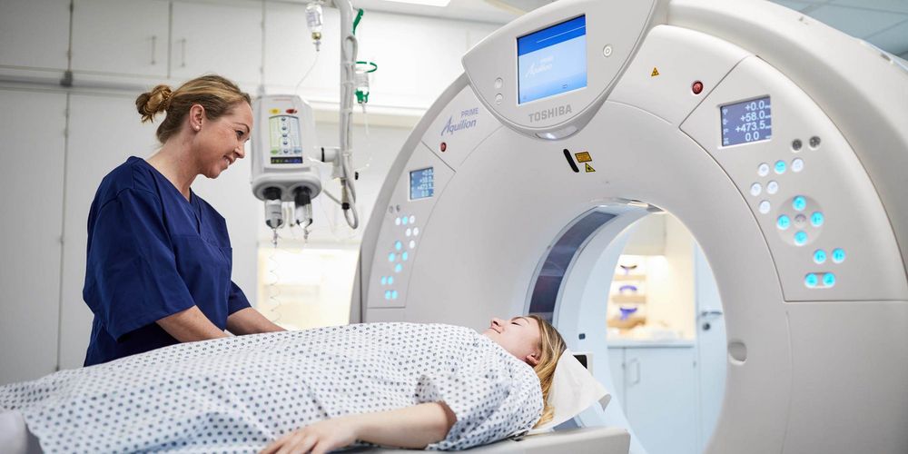 Eine Mitarbeiterin der lokalen Tumortherapie bereitet eine Patientin auf ein CT vor.