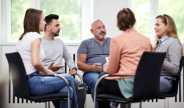Das Bild zeigt fünf Menschen bei einer Gruppentherapie.