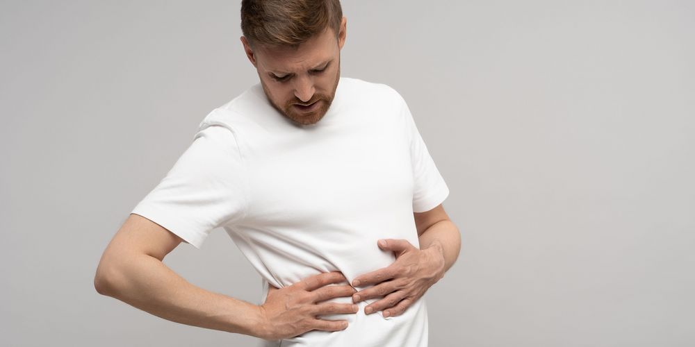 Ein Mann leidet unter Druckschmerz im Bauch, ein Symptom für Leberkebs.