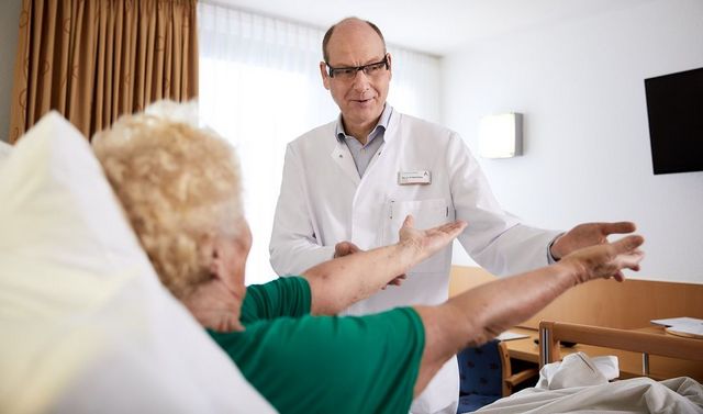 Bewegungstherapie – Leistung in der ambulanten Pflege Ein Arzt und eine Patientin bei der Bewegungstherapie, eine Leistung in der ambulanten Pflege.