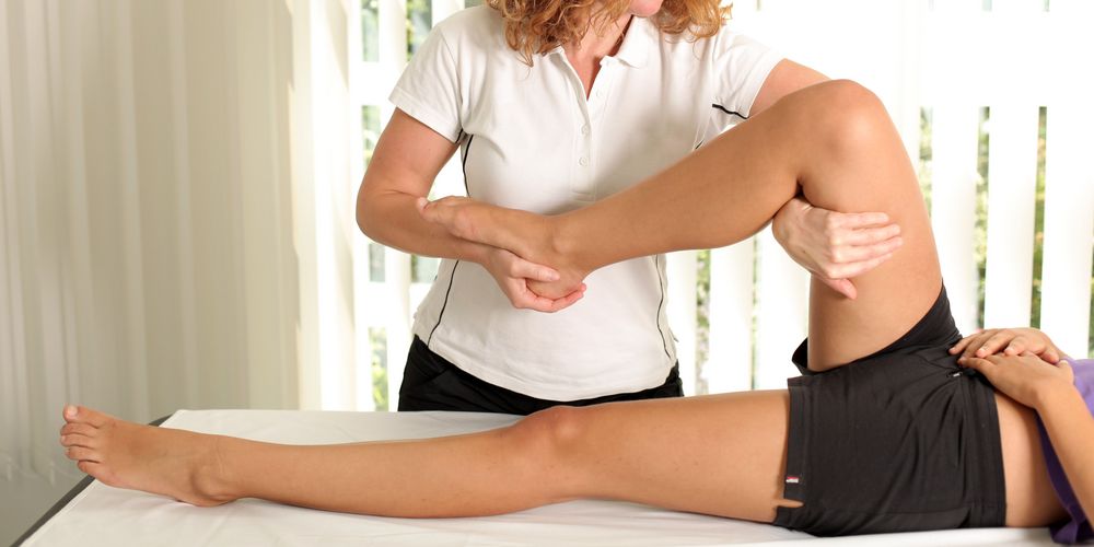 Eine Physiotherapeutin führt mit einer Betroffenen Übungen durch zur Ischias-Behandlung.
