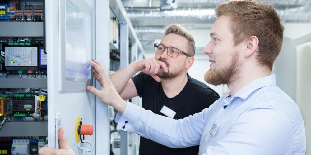 Zwei Mitarbeiter der Haustechnik schauen gemeinsam auf einen Plan. 