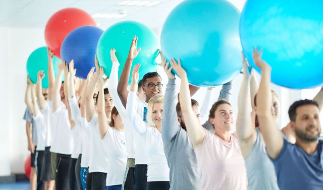 Patientinnen und Patienten führen gemeinsam Übungen in einer Gruppenstunde der Ergotherapie durch.