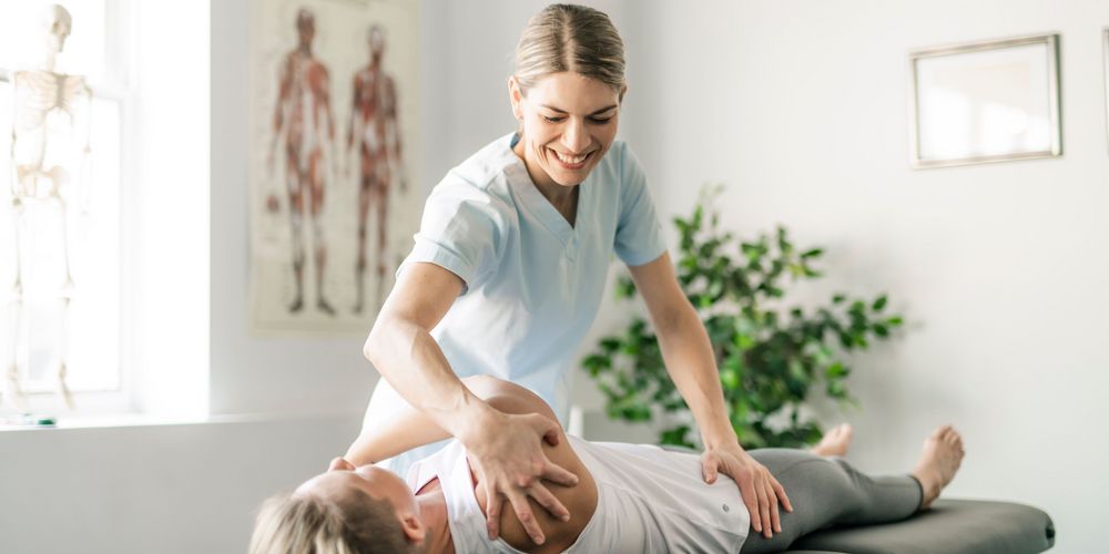 Wann ist eine Spondylodese-OP sinnvoll? Eine Frau mit Rückenschmerzen probiert bei der Physiotherapie zunächst konservative Maßnahmen vor einer Spondylodese.