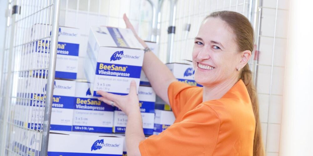 Eine Frau greift ein Paket von einem Wagen in einem Flur. 