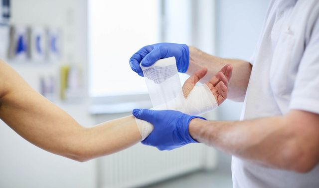 Ein Arzt verbindet die Hand einer Patientin in der Notfallsprechstunde der orthopädischen Ambulanz. 