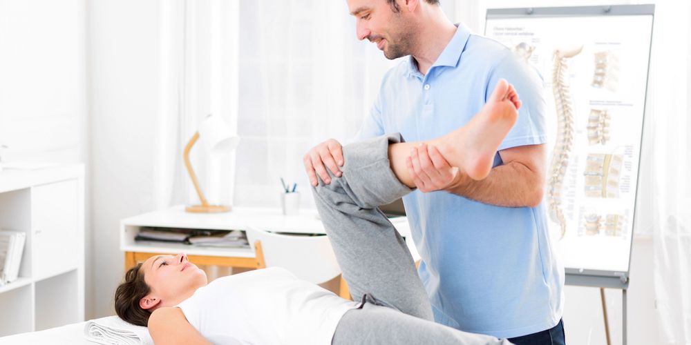 Ein Physiotherapeut betreut eine Patientin nach einem Bänderriss. 