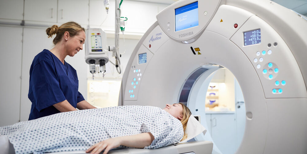 Eine Mitarbeiterin der Orthopädie bereitet eine CT-Untersuchung für eine Patientin vor.