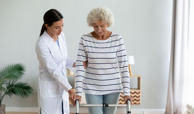 Eine Ärztin hilft einer betroffenen Frau, die Symptome einer Myopathie aufweist, beim Gehen.