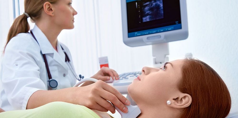 Eine Ärztin für Viszeralchirurgie untersucht die Schilddrüse einer Patientin.
