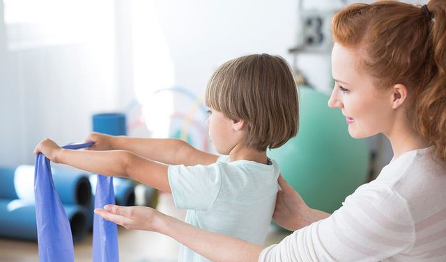 Eine Mitarbeiterin der Kinderorthopädie und ein Patient bei der Krankengymnastik.