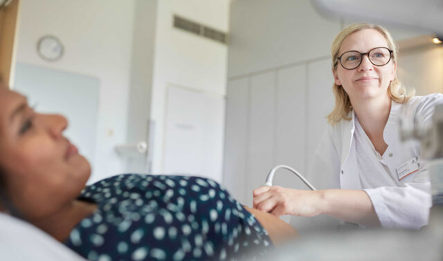 Eine Ärztin aus dem Fachbereich Geburtshilfe nimmt einen Ultraschall bei einer schwangeren Frau vor.  