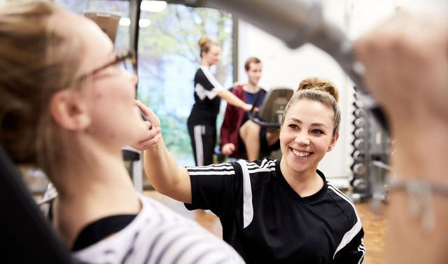 Eine Trainerin unterstützt beim Gesundheitstraining.