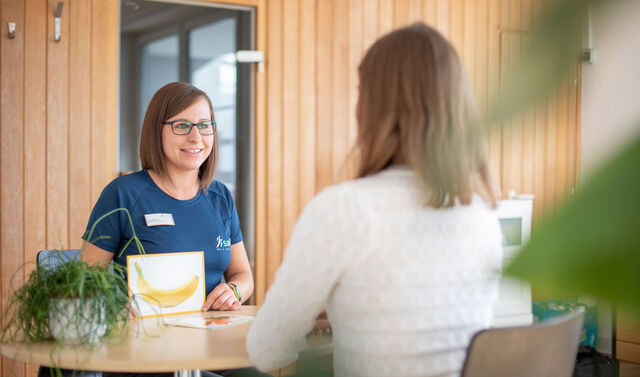 Logopädin zeigt der Patientin eine Karte mit einer Banane und übt mit ihr die Aussprache