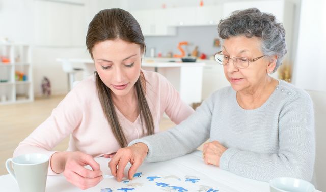 Die Grafik zeigt eine von Demenz betroffene Frau mit einer Angehörigen beim Trainieren des Gedächtnisses durch Puzzeln.