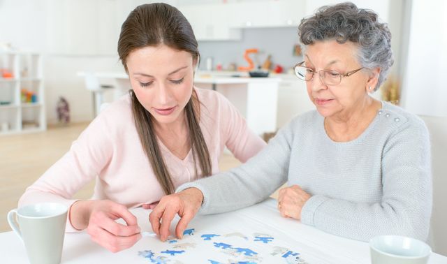 Die Grafik zeigt eine von Demenz betroffene Frau mit einer Angehörigen beim Trainieren des Gedächtnisses durch Puzzeln.