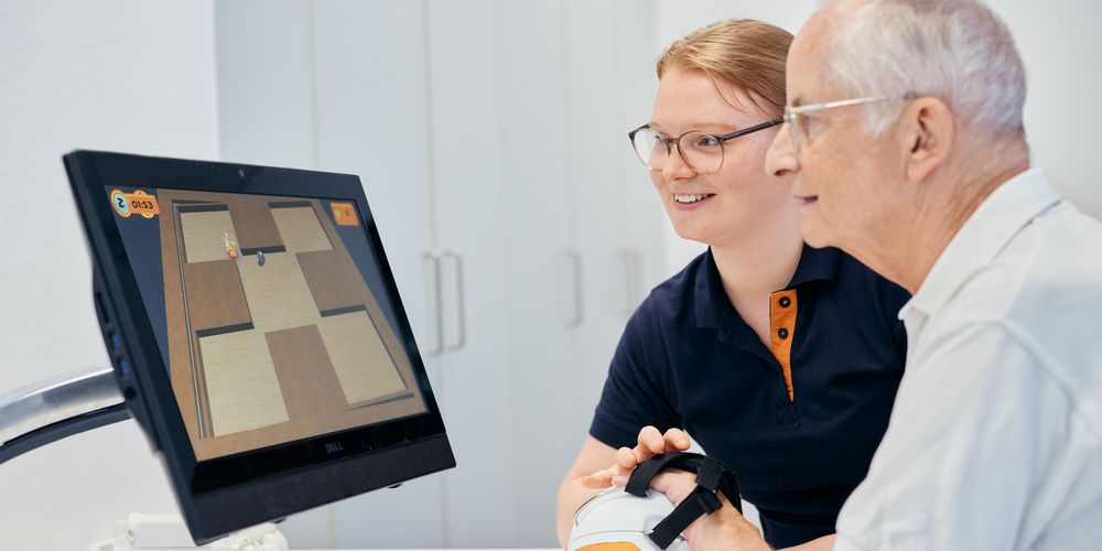Mit einer Ergotherapeutin führt ein Patient gezielten Übungen bei der Ergotherapie durch.