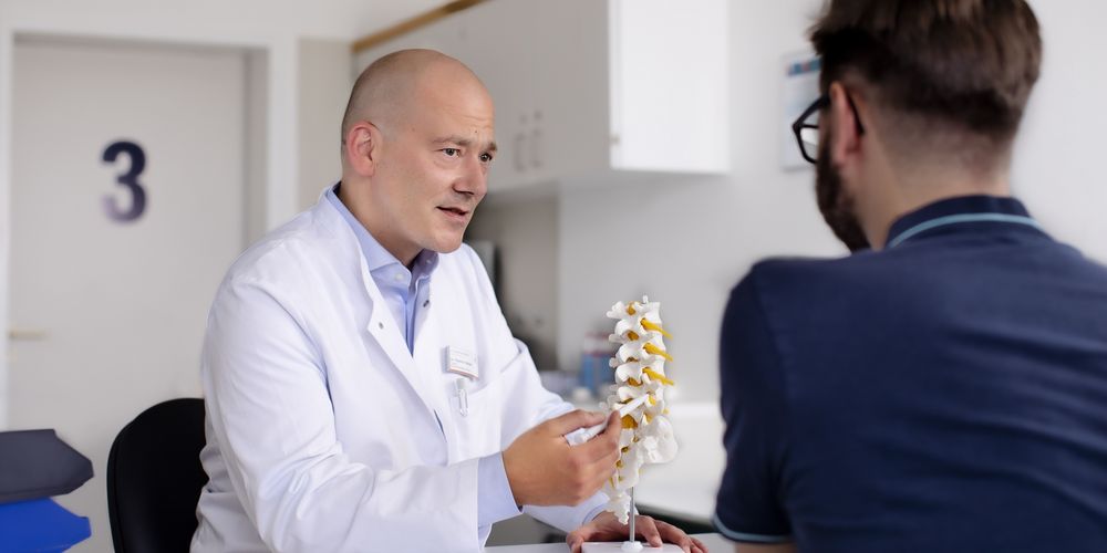 Ein Facharzt für Unfallchirurgie berät einen Patienten zu den Behandlungen.