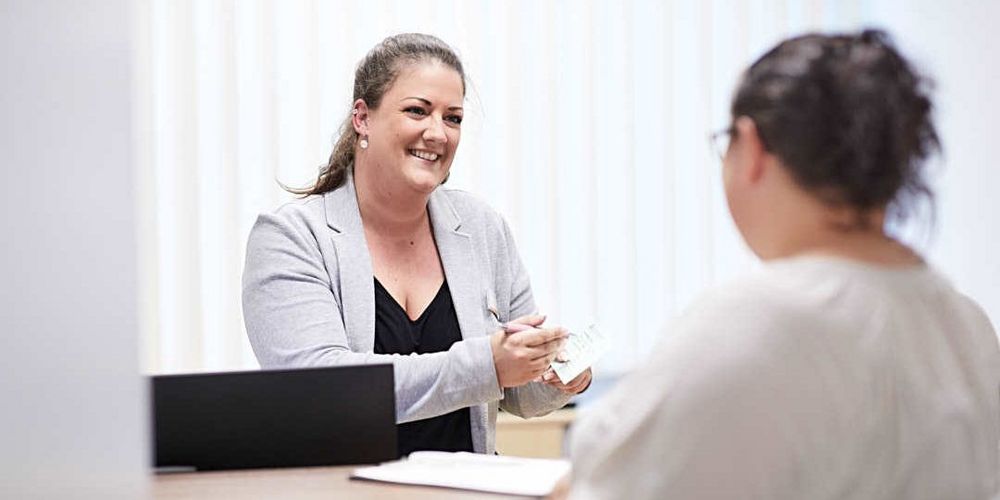 Eine Mitarbeiterin klärt eine Patientin über den Zusammenhang von Bluthochdruck und Übergewicht auf.