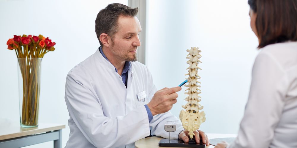 Ein Arzt berät eine Patientin zur Behandlung ihres Bandscheibenvorfalls.