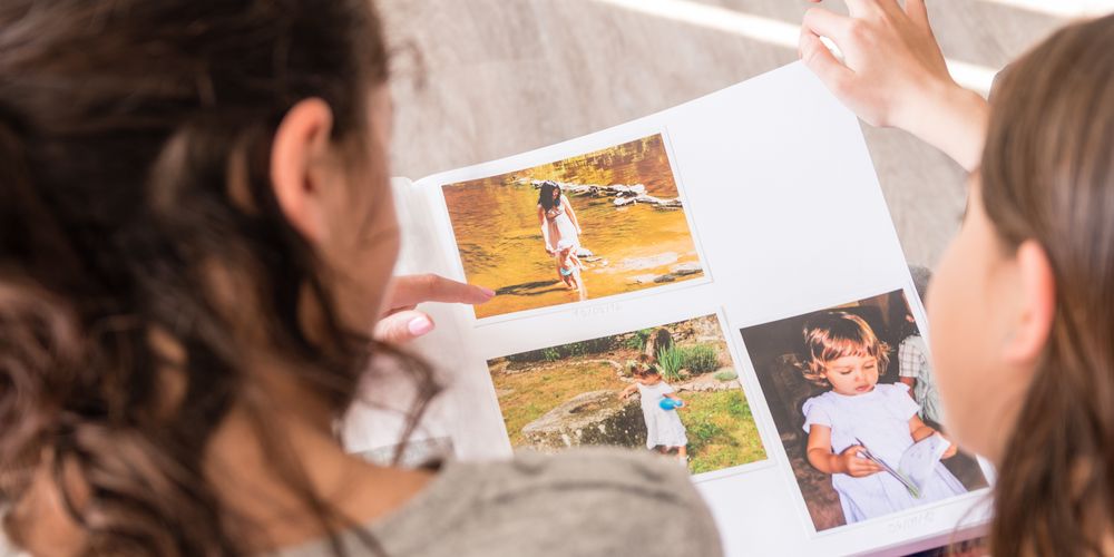 Die Ursache für Ängste kennen, um diese behandeln zu können Eine Mutter schaut mit ihrer Tochter ein Fotoalbum an, um Ängste überwinden und verstehen zu können.