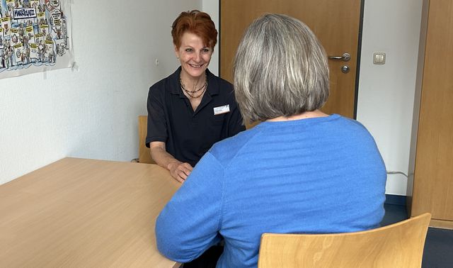 Dagmar Mende sitzt einer Angehörigen an einem Tisch gegenüber und führt mit ihr ein persönliches Beratungsgespräch.