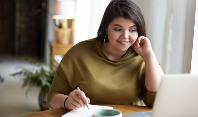 Eine Frau sitzt am Tisch vor ihrem Laptop und notiert sich Methoden zum Abnehmen ohne OP bei Adipositas.