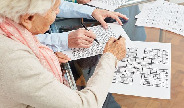 Gedächtnistraining – besondere Leistung in der ambulanten Pflege Eine Bewohnerin beim Gesellschaftsspiel als Gedächtnistraining, eine Leistung in der ambulanten Pflege.