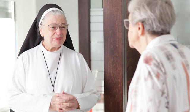 Das Bild zeigt eine Glaubensschwester, die sich mit einer älteren Frau unterhält.