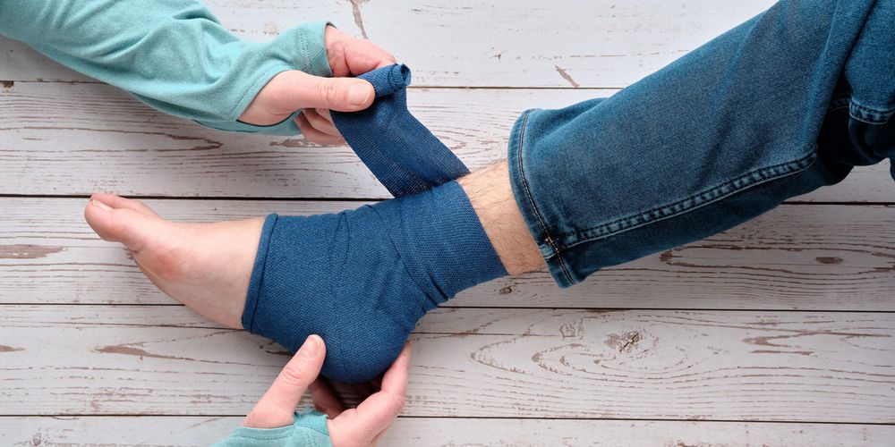 Was passiert bei einer Verstauchung? Eine Ärztin behandelt die Verstauchung eines Patienten beziehungsweise einer Patientin.