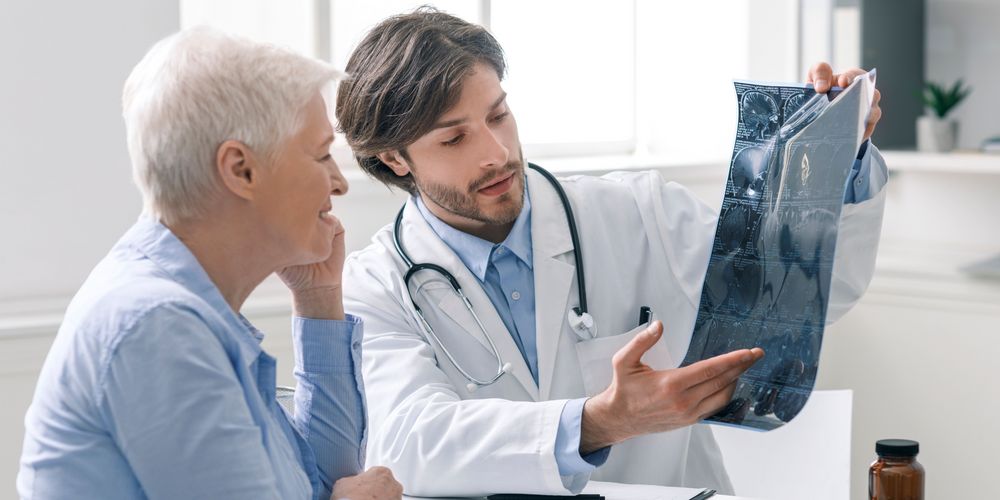 Symptome der frontotemporalen Demenz Ein Arzt informiert einen Patienten mit frontotemporaler Demenz über die Symptome.