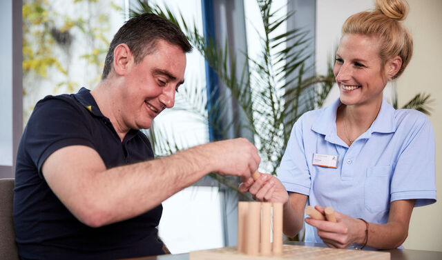 Eine Ergotherapeutin und ein Patient beim therapeutischen Training.