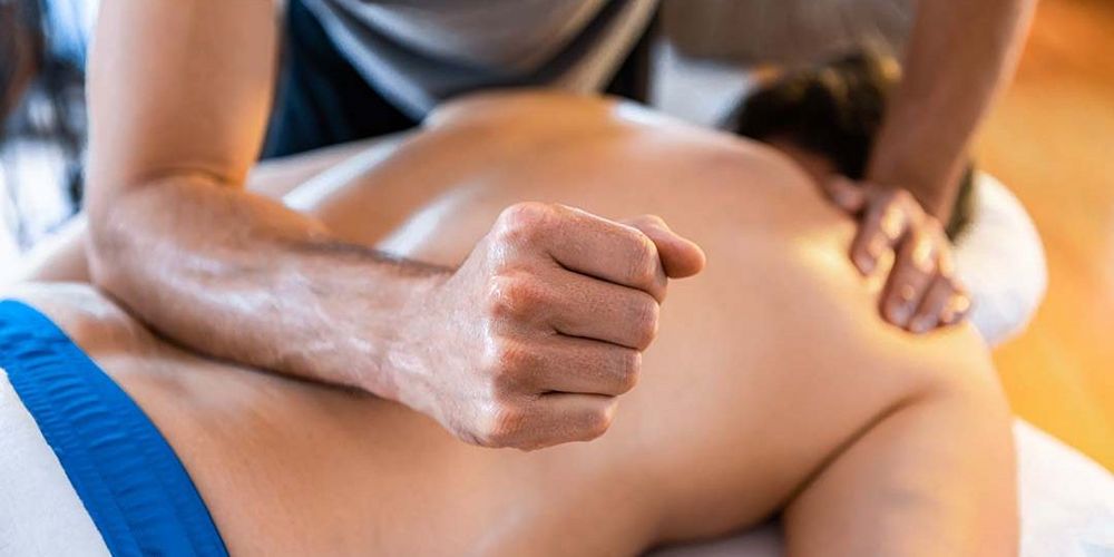 Eine Masseurin führt eine medizinische Massage an einer Patientin durch.