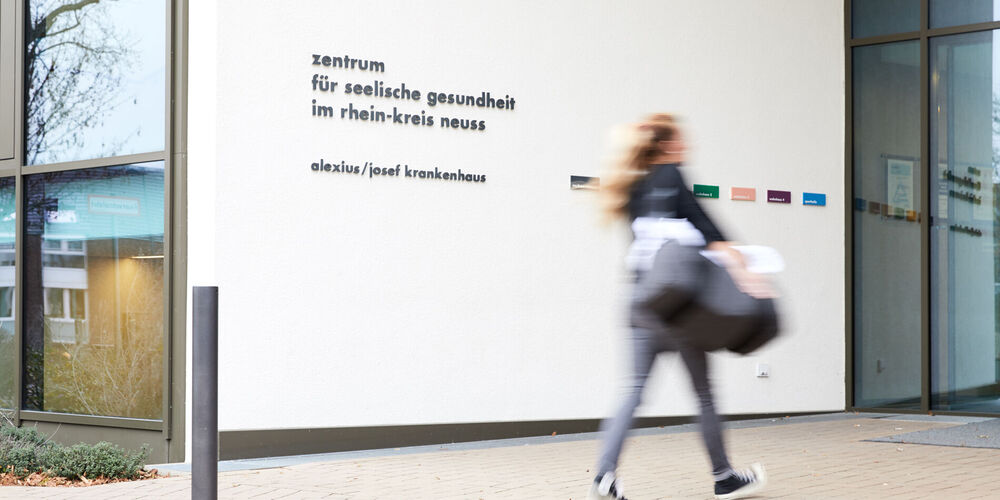 Eine Patientin geht in die Klinik, um eine Erkrankung in der Psychiatrie behandeln zu lassen.