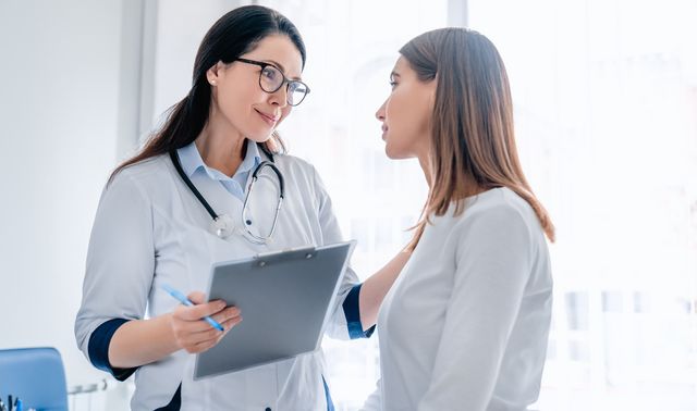 Eine Patientin lässt sich ein Ultraschallbild von ihrem Arzt aufgrund ihrer Schilddrüsenüberfunktion erklären.