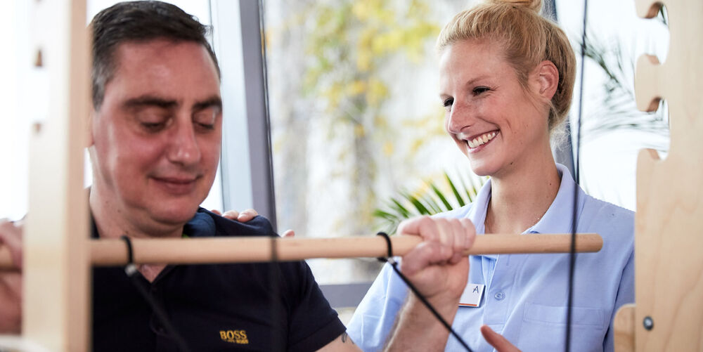 Eine Mitarbeiterin des therapeutischen Trainings betreut einen Patienten.