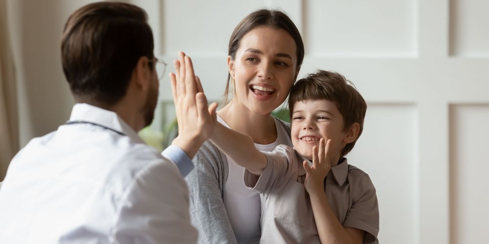 Ein Junge mit Rett-Syndrom gibt seinem behandelnden Arzt ein High-Five.