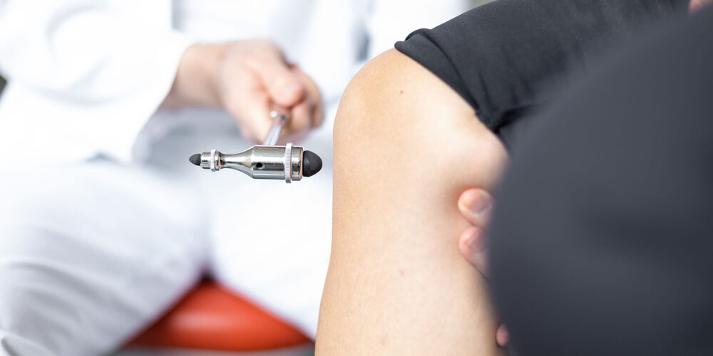 Ein Facharzt der Orthopädie untersucht das Knie eines Patienten.