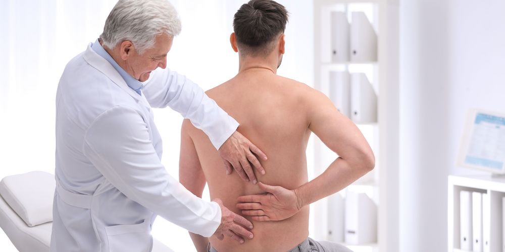 So diagnostizieren Ärztinnen und Ärzte eine Entzündung an der Wirbelsäule Ein Arzt untersucht den Rücken eines Patienten auf Anzeichen einer Entzündung.