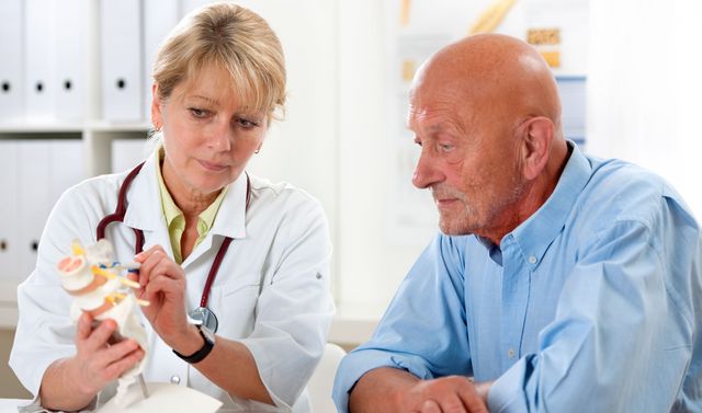 Eine Ärztin erklärt einem Patienten die Symptome bei einer Wirbelblockade.