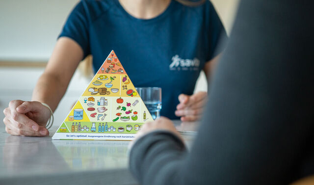 Eine Mitarbeiterin aus dem Fachbereich Adipositas spricht mit einer Patientin über die Ernährungspyramide.