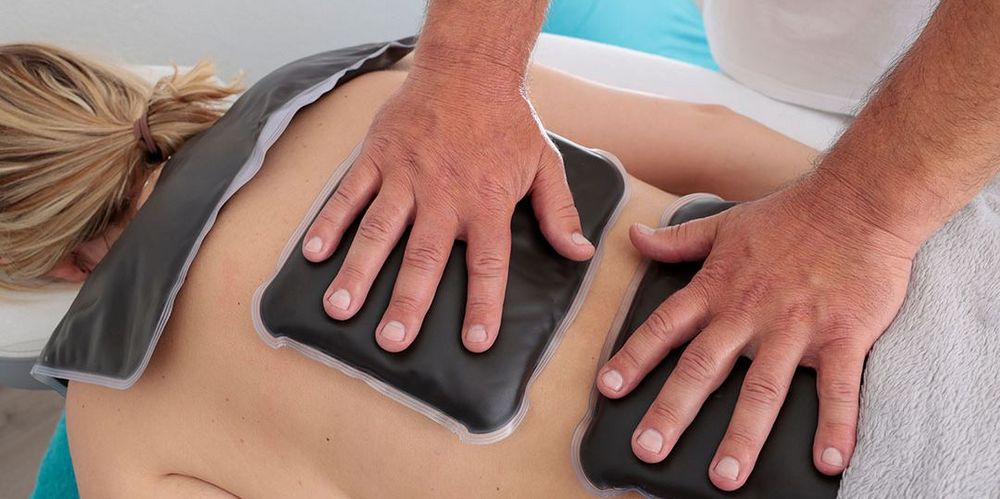 Die medizinische Massage einer Patientin wird mit Hilfsmitteln unterstützt.