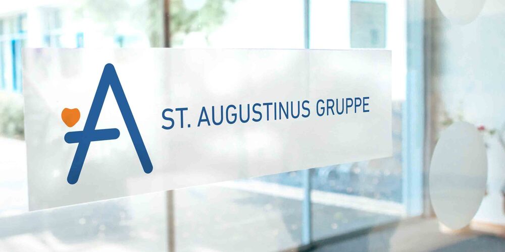 Gläserne Eingangstür, welche das Logo der Augustinus Gruppe trägt.