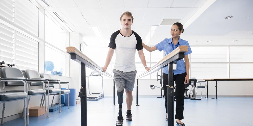 Eine Therapeutin hilft einem Patienten nach einer Amputation durch orthopädische Reha seine Ziele zu erreichen. 