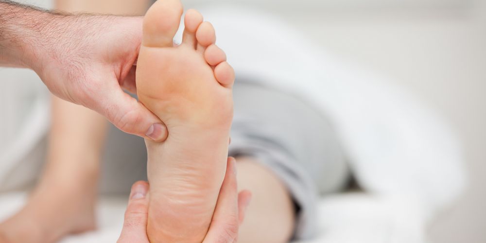 Eine Orthopädin untersucht den Fuß einer Patientin, um die Diagnose Bänderriss bestätigen zu können.