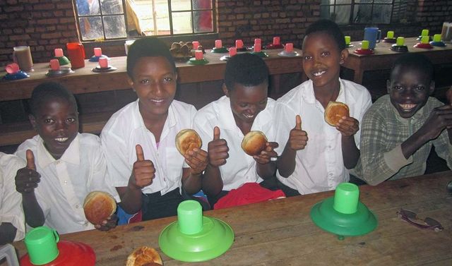 Spenden Burundi Schulfrühstück Kinder aus Afrika sitzen an einem Tisch und frühstücken.