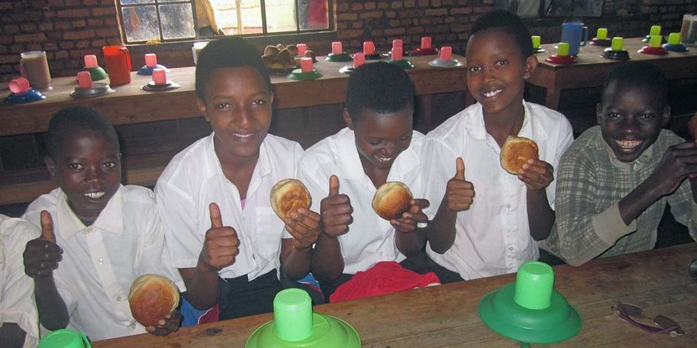 Kinder aus Afrika sitzen an einem Tisch und frühstücken.