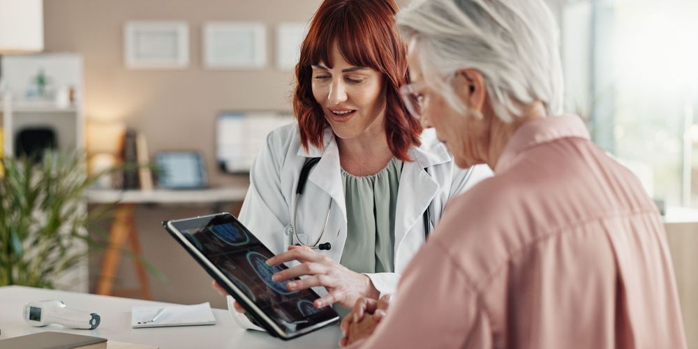 Die Grafik zeigt, wie eine Ärztin einer Patientin die Aufnahmen des Gehirns mit vaskulärer Demenz erklärt.